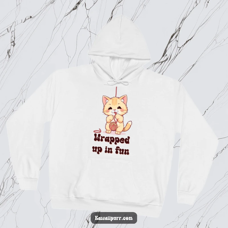 Funny fuzzy cat hoodie, depicted playfully swiping at a dangling ball of yarn, designed for ultimate comfort and charm.